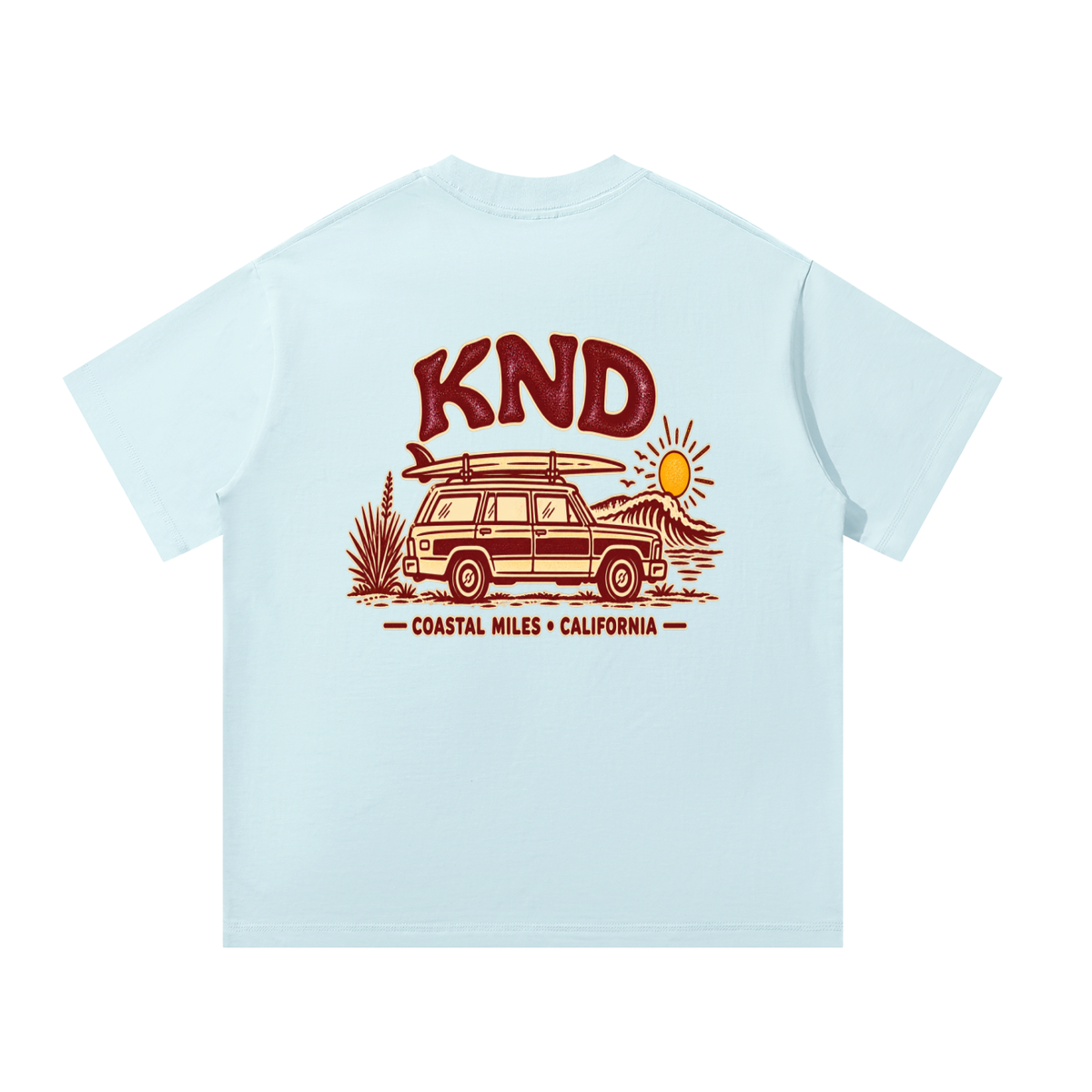 Coastal Miles Tee, Sky Blue — back print: a woodie station wagon with a surfboard on the roof beside a curling wave, under burgundy KND lettering and “Coastal Miles · California”