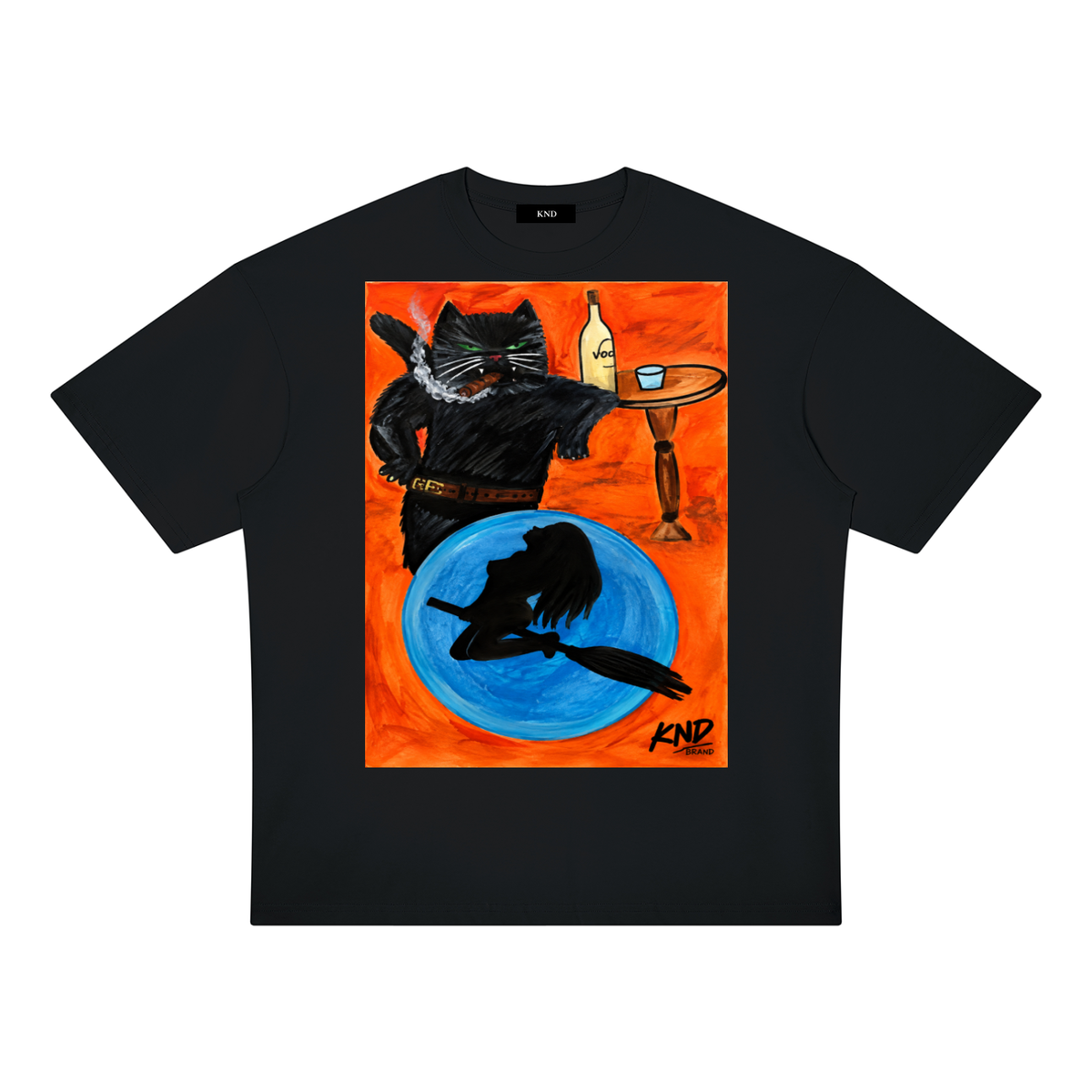 Behemoth Oversized Tee, Black — front print, hand-drawn black cat standing upright in a belt with a cigar, beside a table with a bottle and glass, and a witch on a broom silhouetted against a blue moon, on an orange background