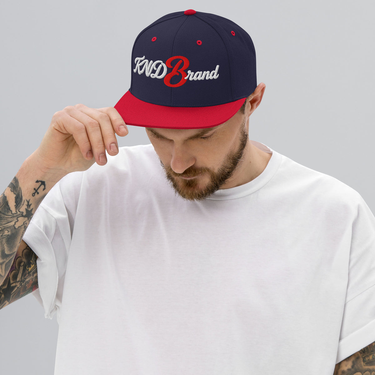 KND Script Snapback in navy with a red bill — white KND Brand script with a red B embroidered front, front view