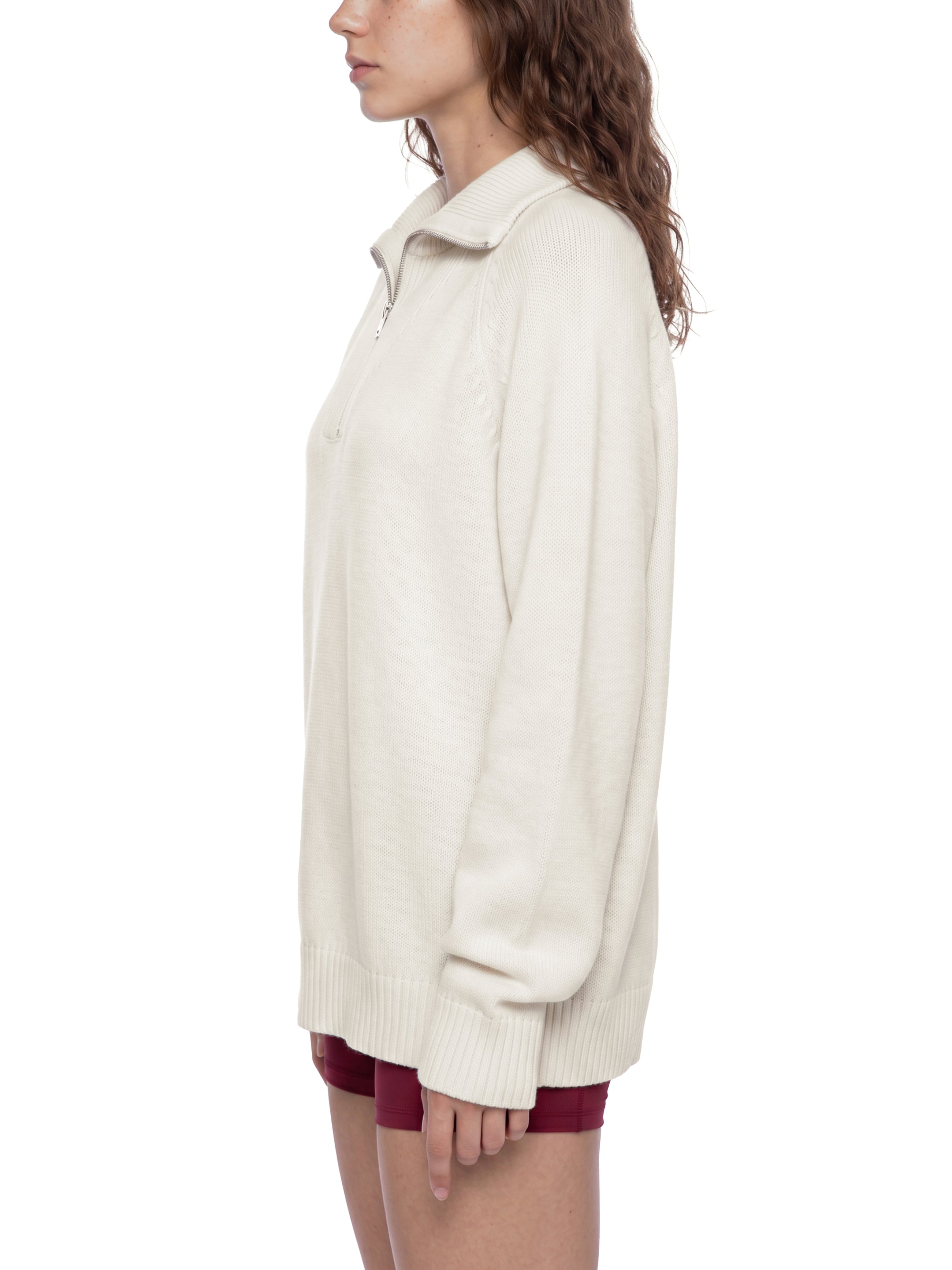 Female model wearing the KND Brand quarter-zip cotton sweater, three-quarter view