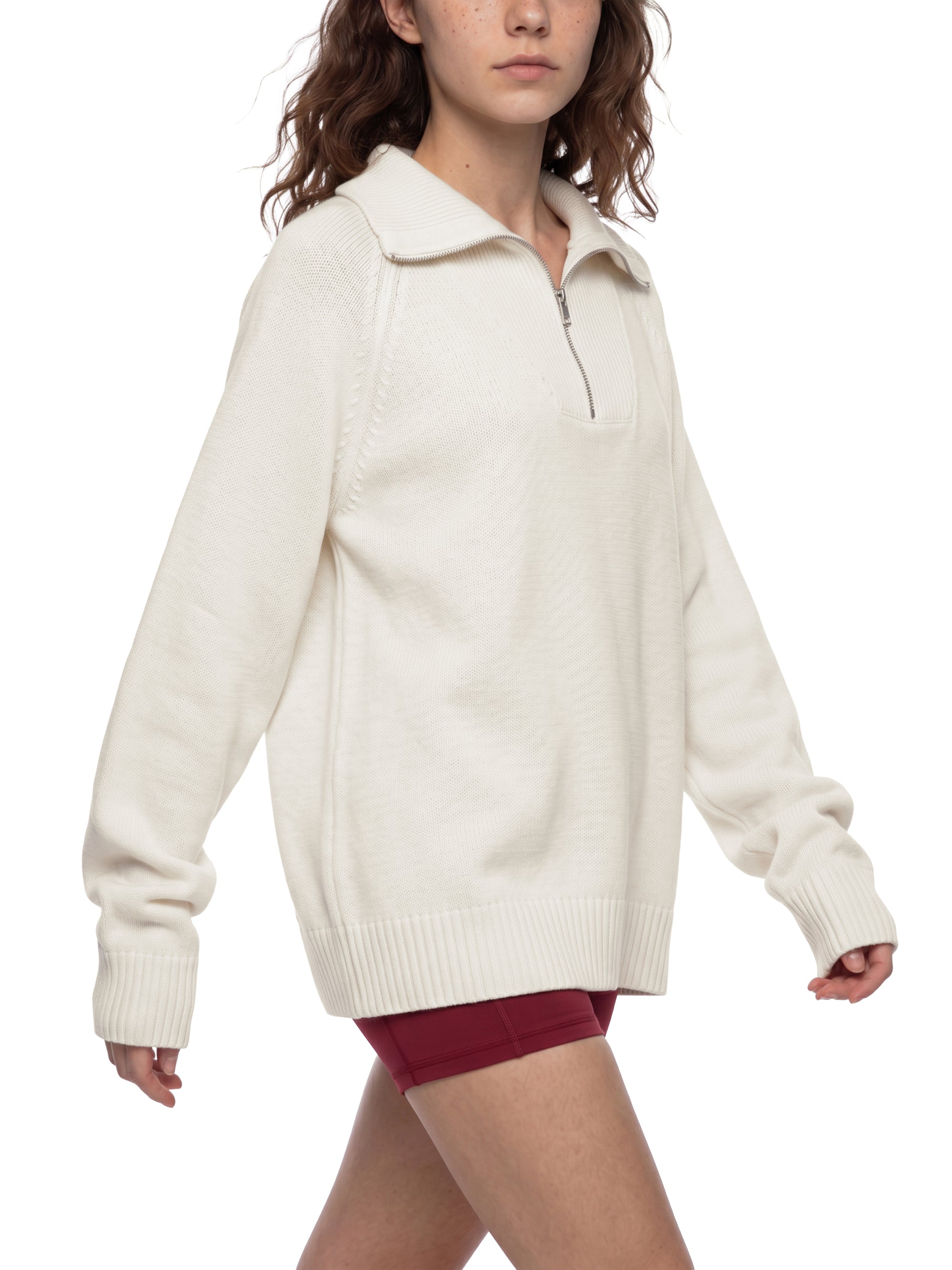 Female model wearing the KND Brand quarter-zip sweater, side profile showing raglan sleeve